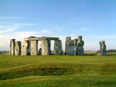 Die stehenden Steine von Stonehenge inmitten einer grünen Wiese und unter blauem Himmel